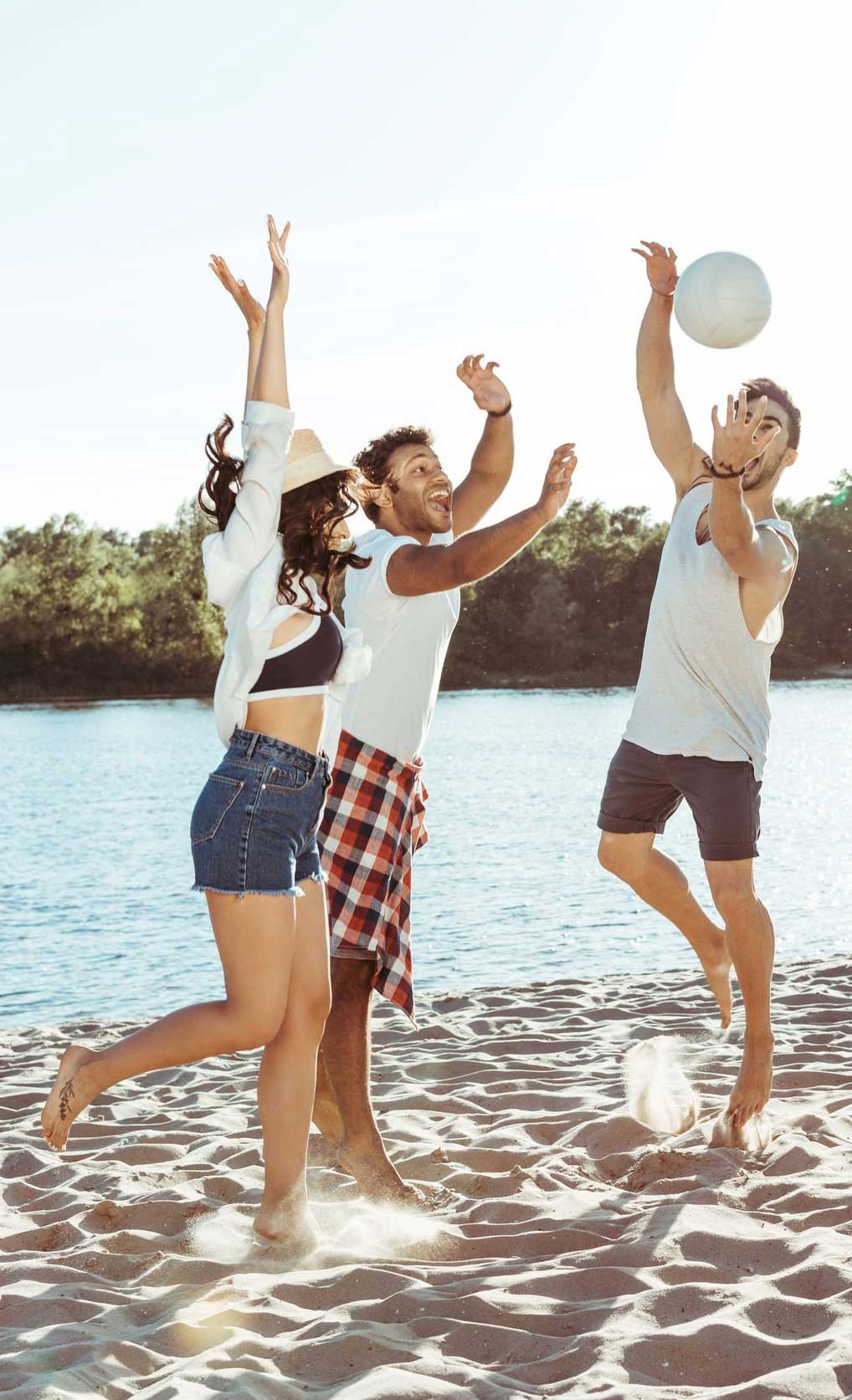 Friends playing volleyball on sandy